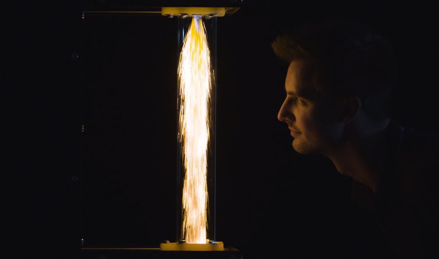 This image shows a man looking at the burning of metal powder for sustainable fuel for industries 