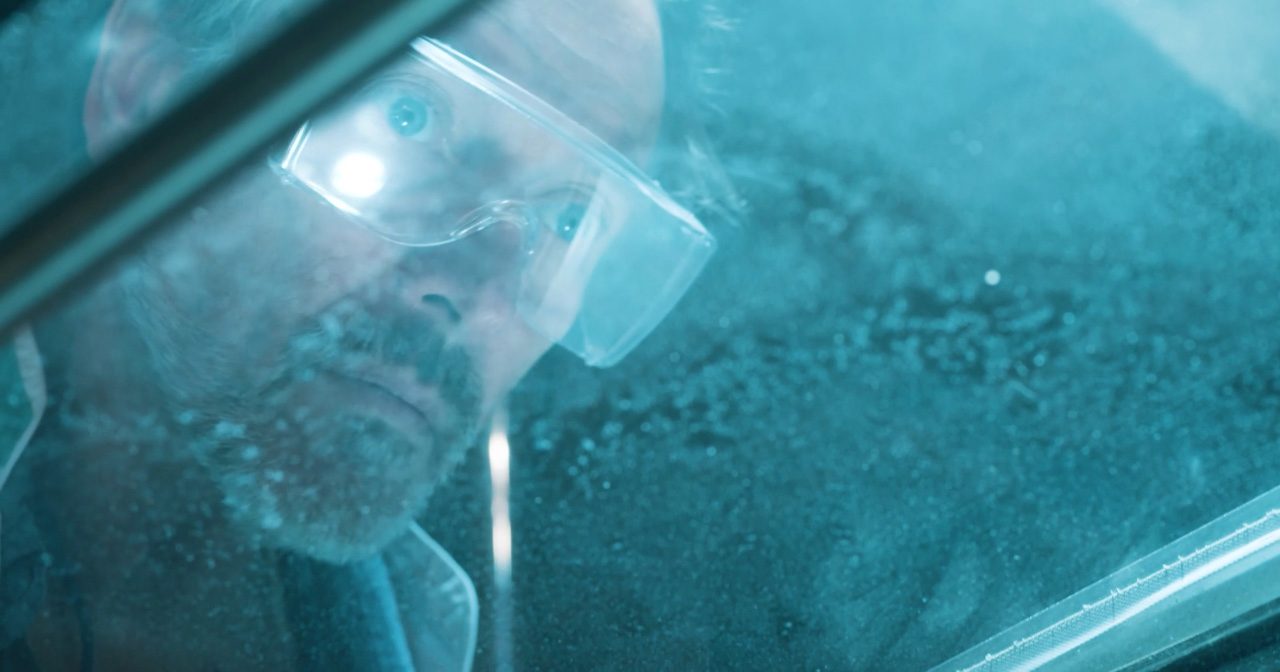 This image shows man wearing safety glasses looking through window