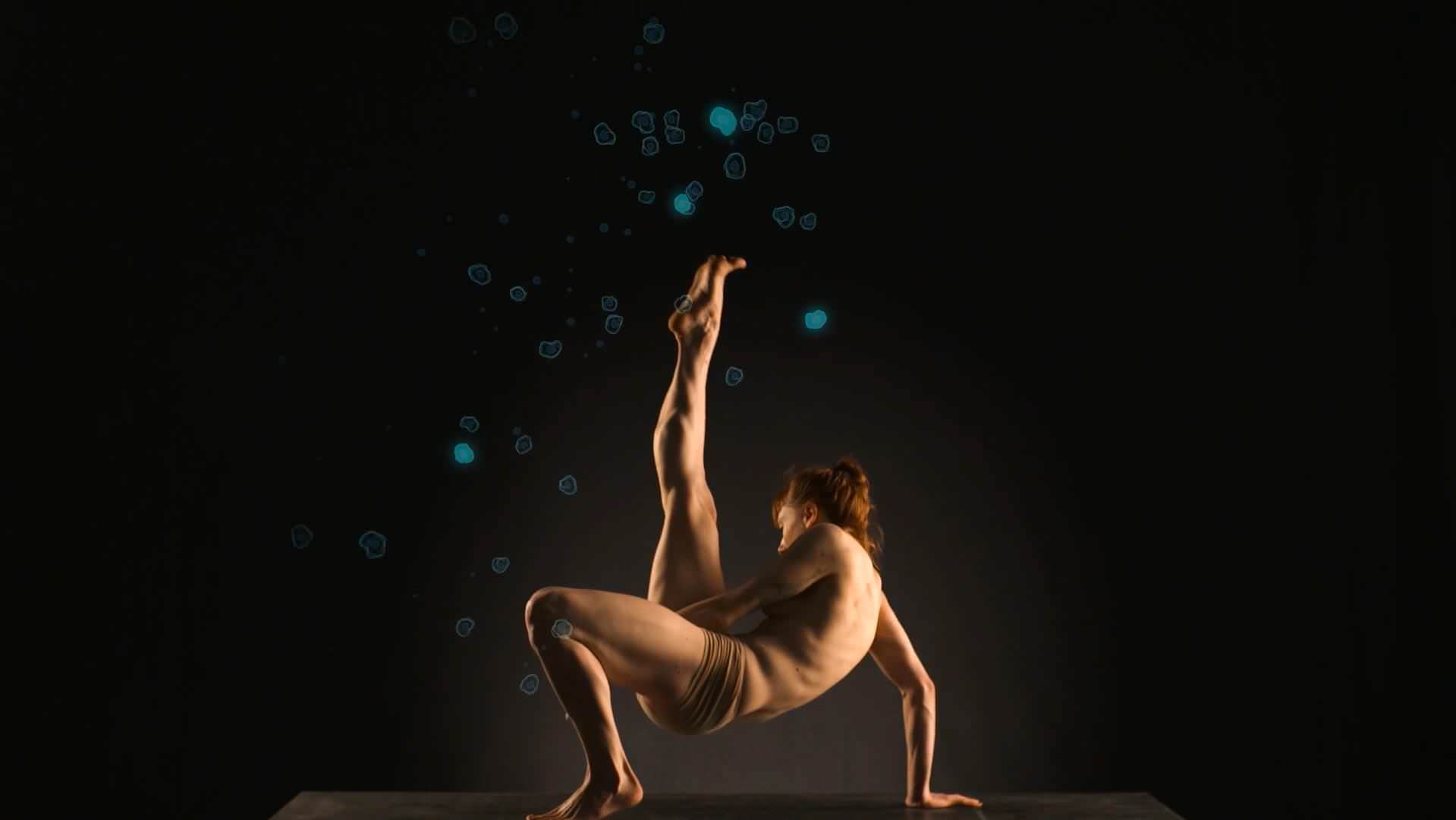 This image shows a dancer lifting her right leg while being surrounded by 3D animated proteins