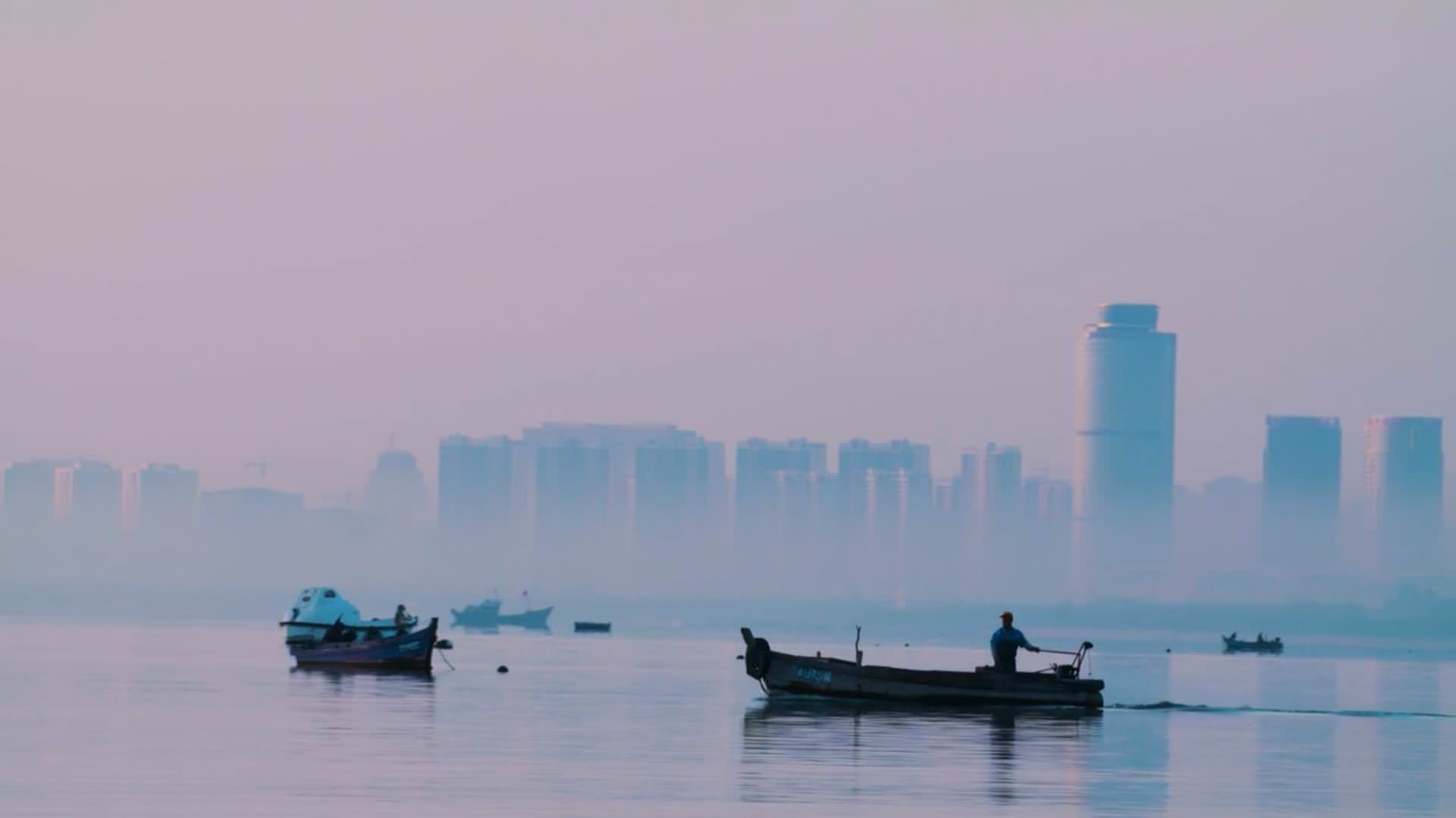 Cinematic image of a small boat in the port of Yantai with the skyline in the background