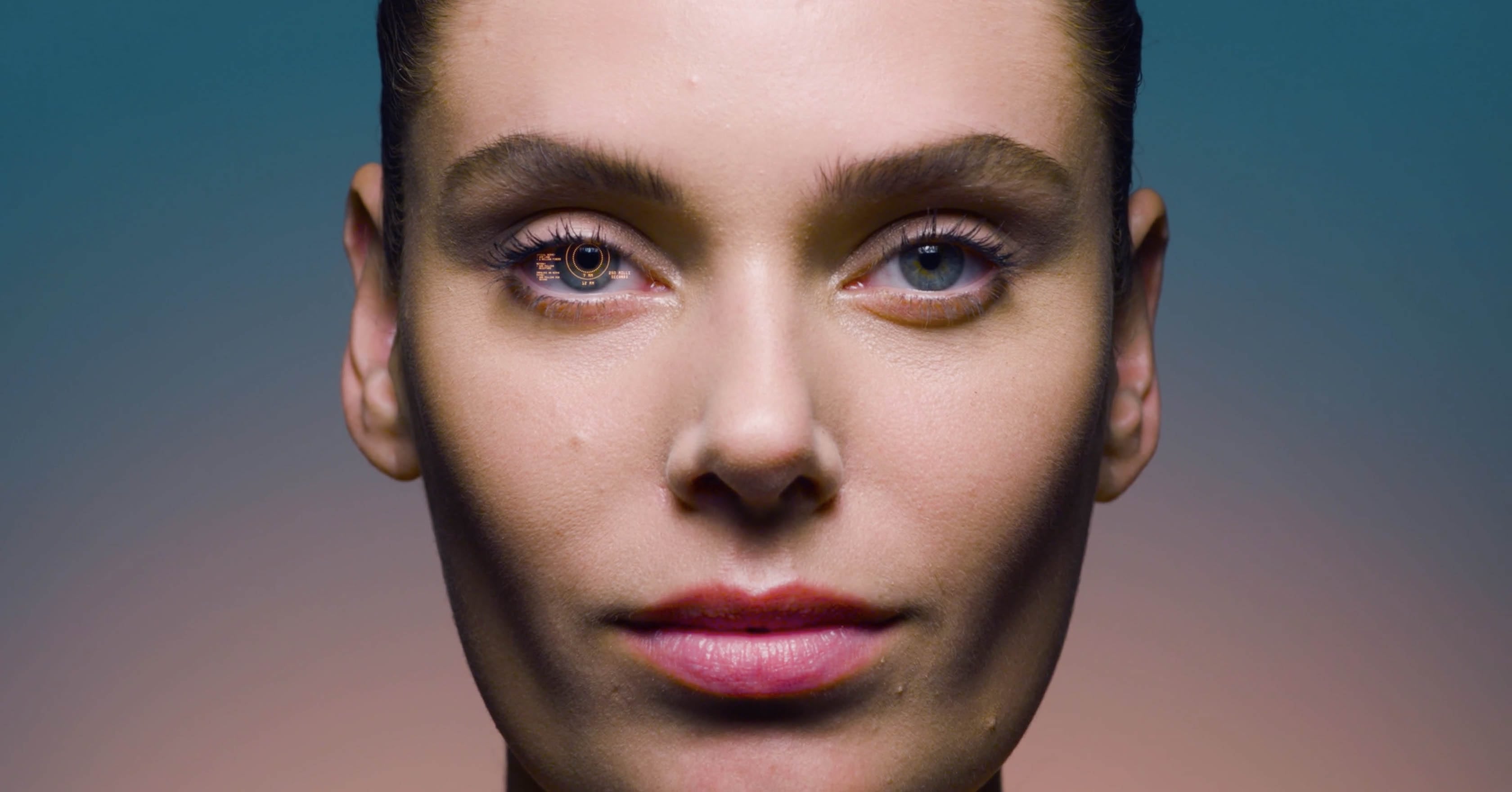 This image shows the face of a female model looking straight in the camera with a HUD on her right eye 